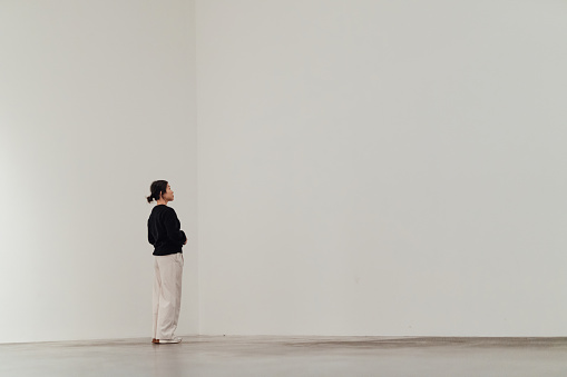 A simple white room with a Woman wandering.