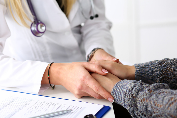 Friendly female doctor hold patient hand in office during reception. Examination result, positive test, calm down, promise and cheer up, grief and suffer, treatment, condolence, ethics concept