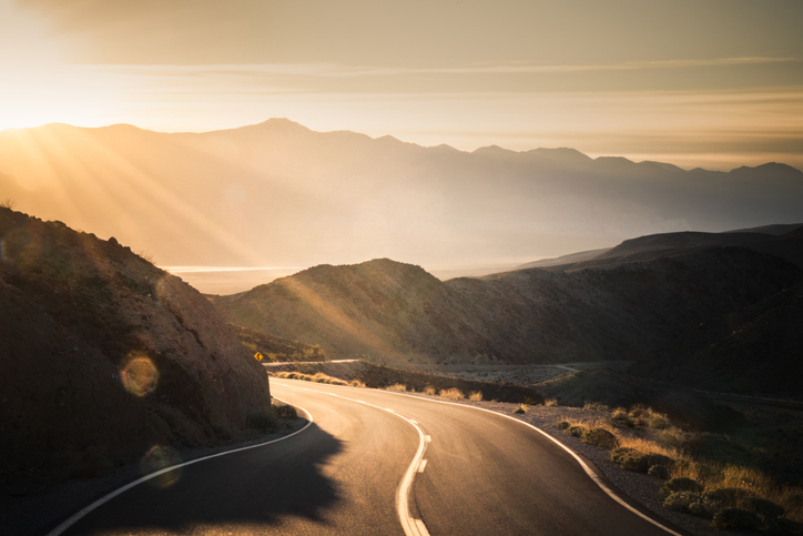 Highway at sunrise, going into Death Valley National Park - stock photo