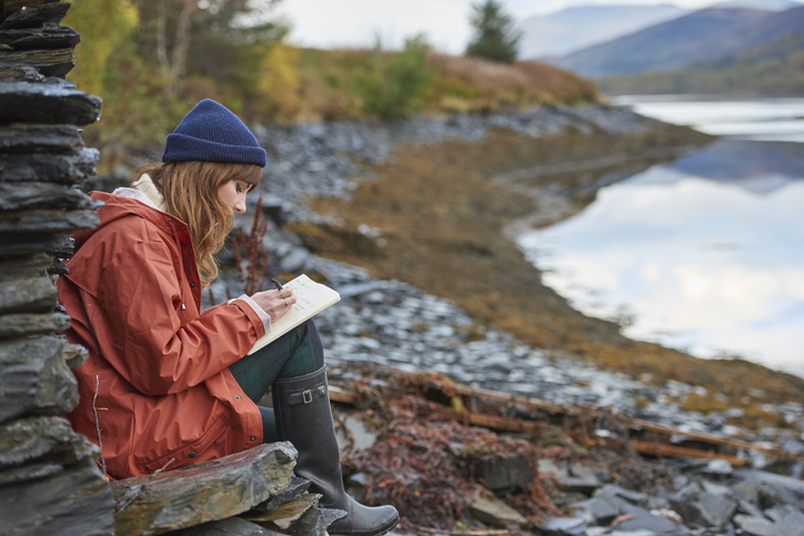 Woman writing in a journal - stock photo