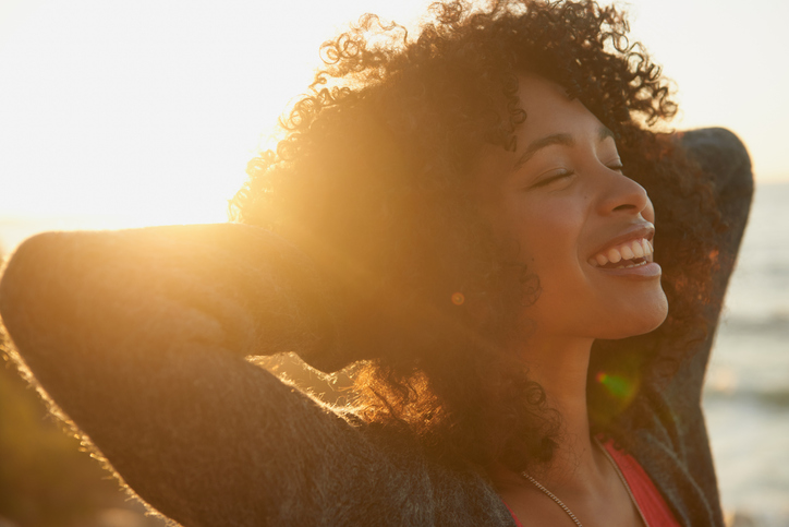 woman smiling with a sunset behind her