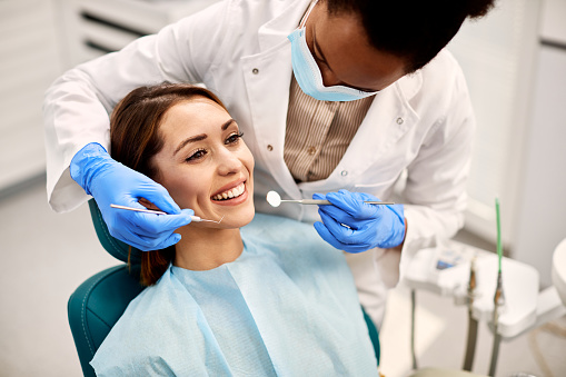 Female pre-dental student cleans female patient's teeth in office