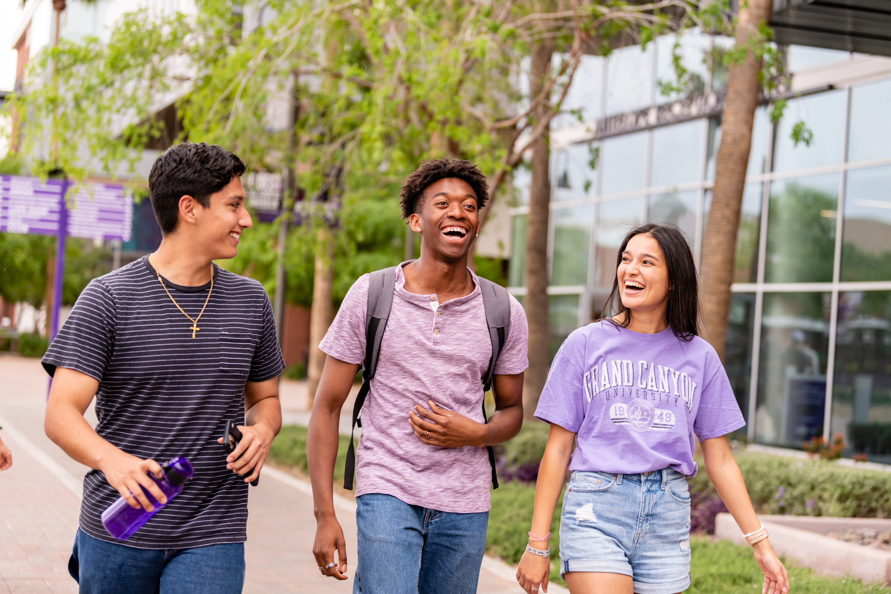 Male and female students laughing and walking outside on GCU's campus